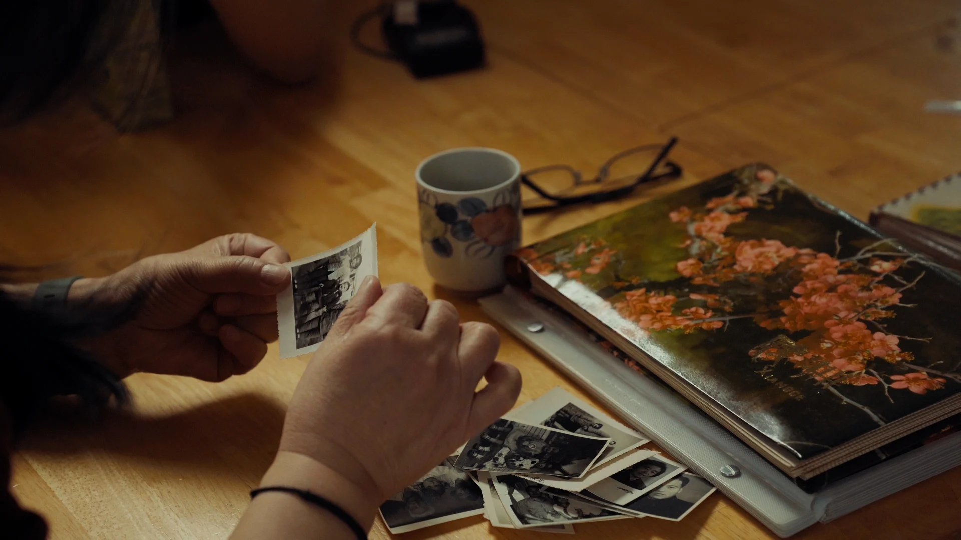 still shot from WHEN ARE YOU COMING HOME? a hand holds old childhood pictures