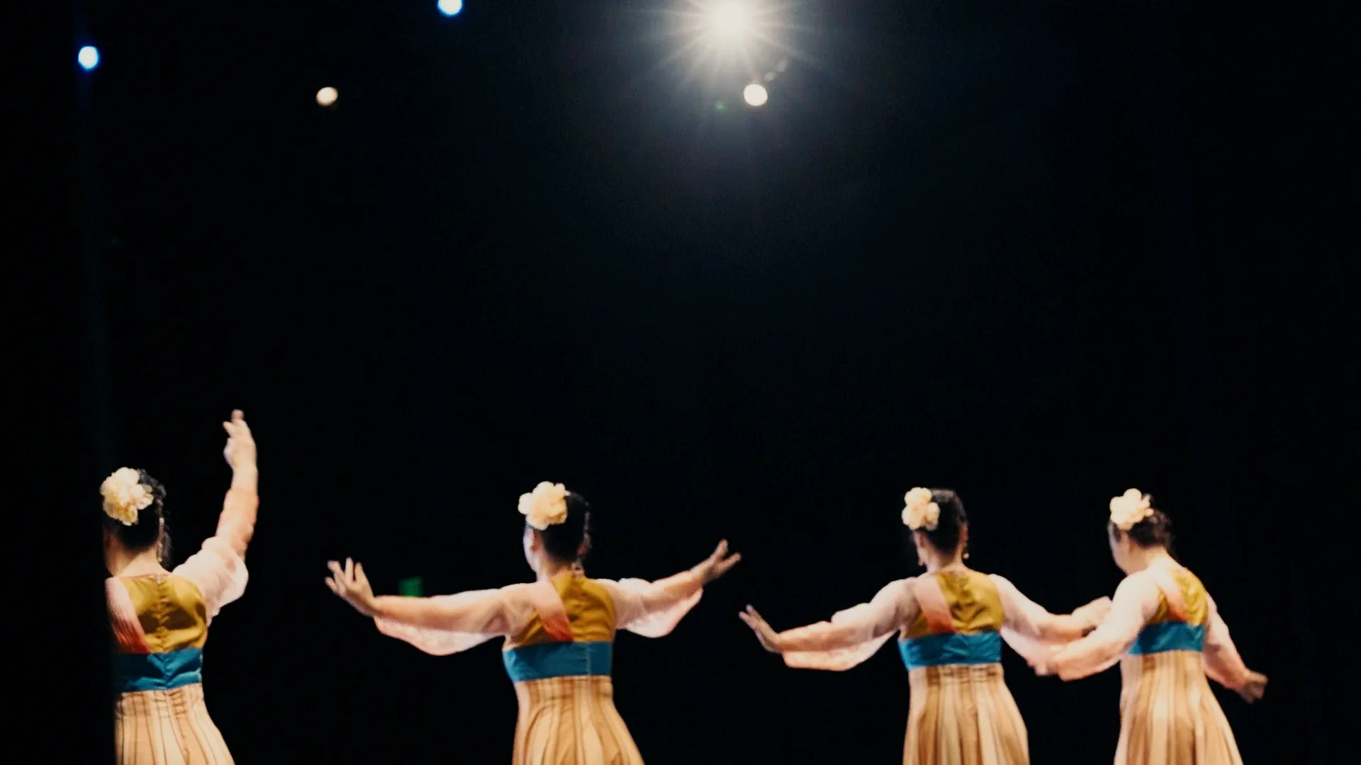 still shot from WHEN ARE YOU COMING HOME? four dancers against a dark auditorium