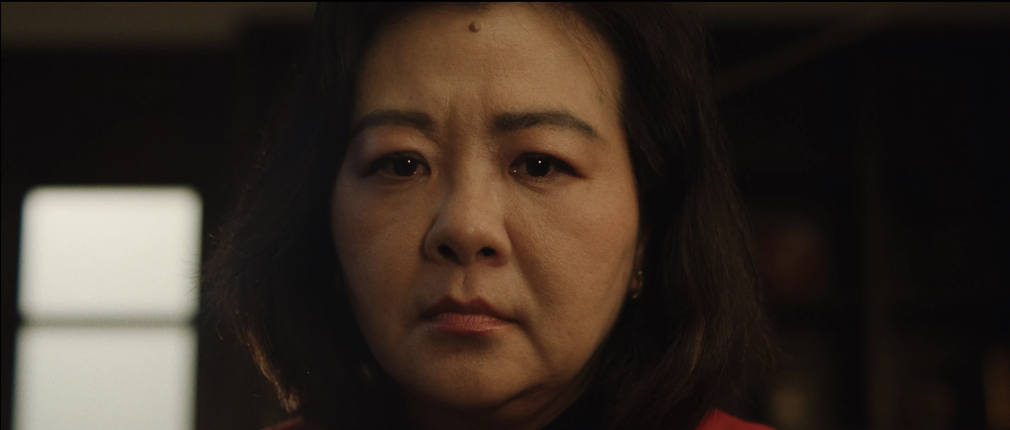 still shot from DID YOU EAT YET? closeup of a woman staring solemnly a head